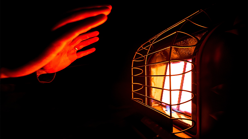 A woman warming her hands in front of a fuel based heater