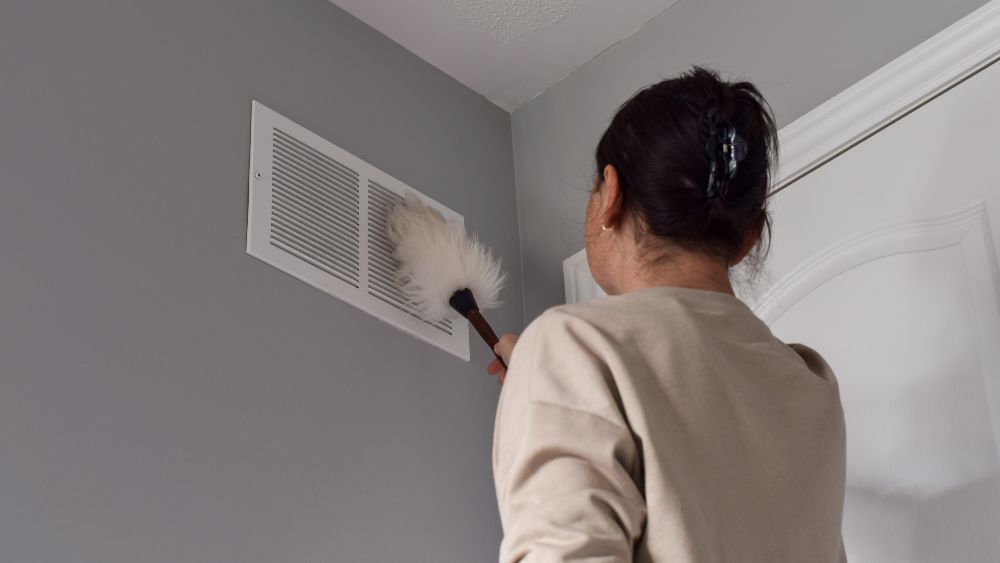 woman cleaning vents to unclog them