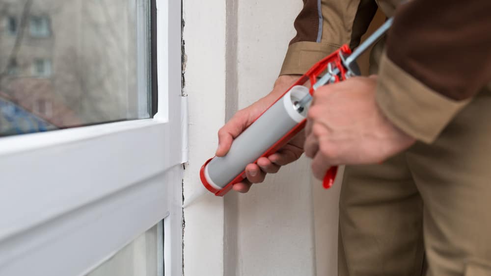 Man insulating a small gap in the door edge.