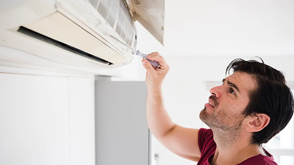 man testing ac for faults because the air conditioner smells bad