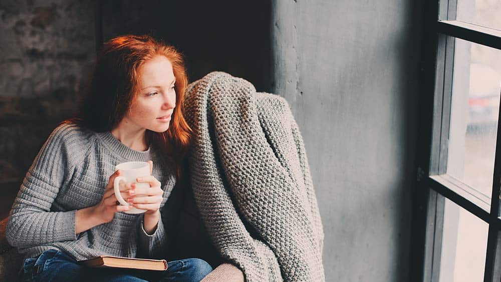 Girl drinking coffee and looking out of the window.