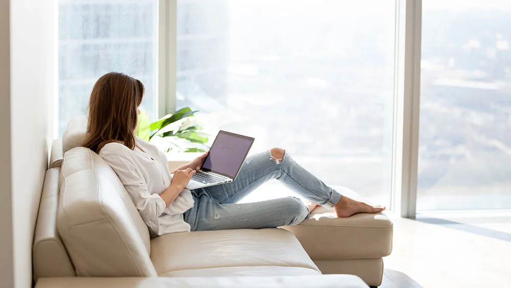 A woman working on her computer in a sunroom