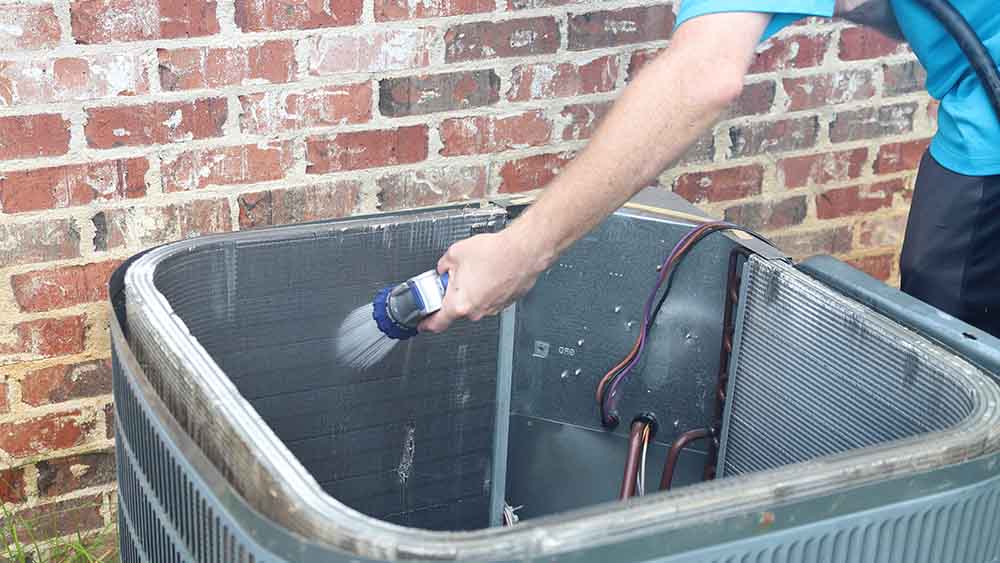 A man cleaning AC outdoor unit