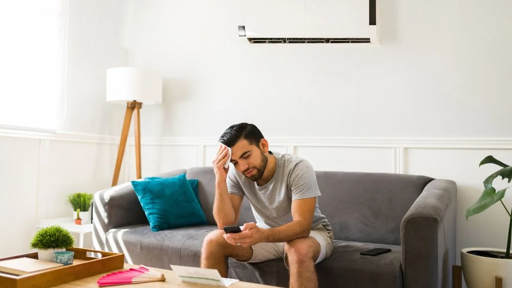 man feeling hot because mini-split ac is blowing hot air