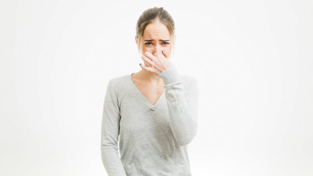 woman holding nose due to stench as its time for an AC tune up