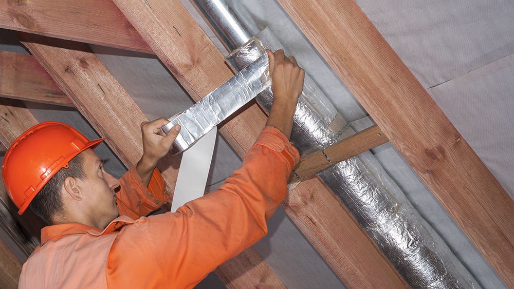 An HVAC technician insulating the the metal ducts