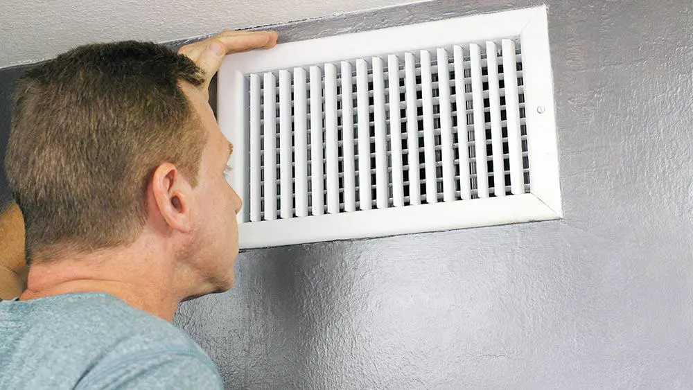 Man checking AC vent.