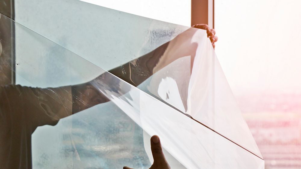 A person installing winow film insulation kit on a window