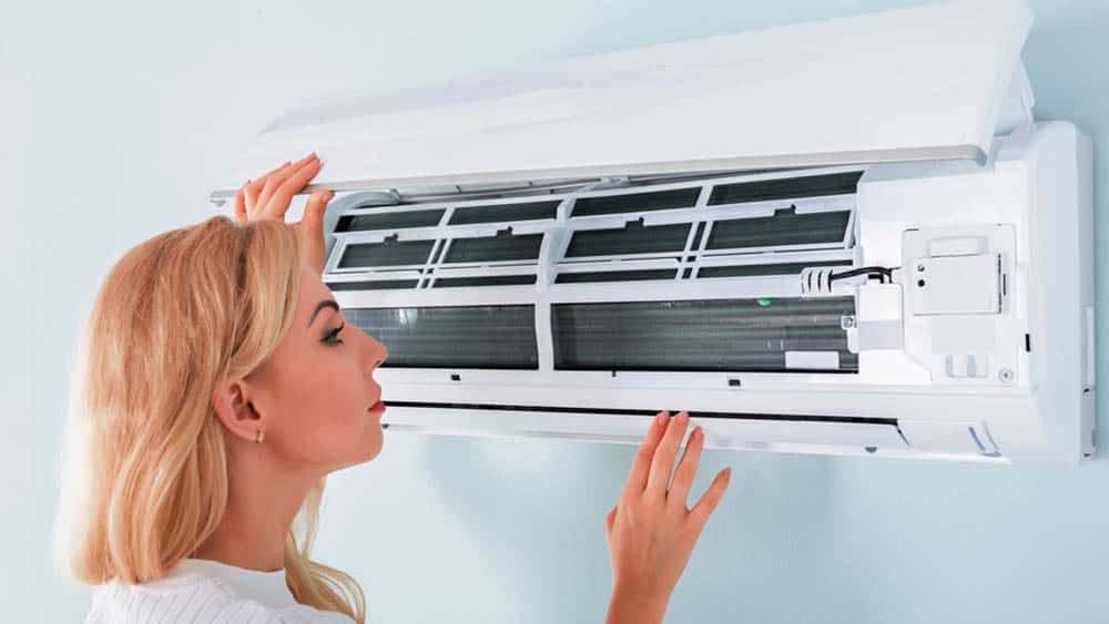 Woman checking her air conditioner.