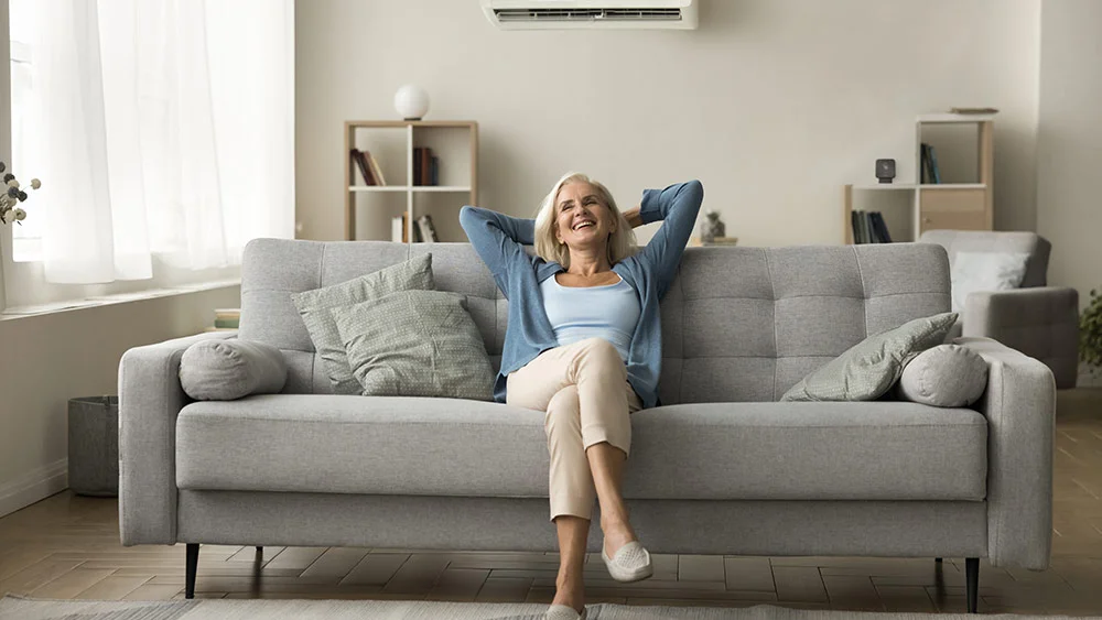 a woman sitting in living room with cielo breez max controlling mini-split