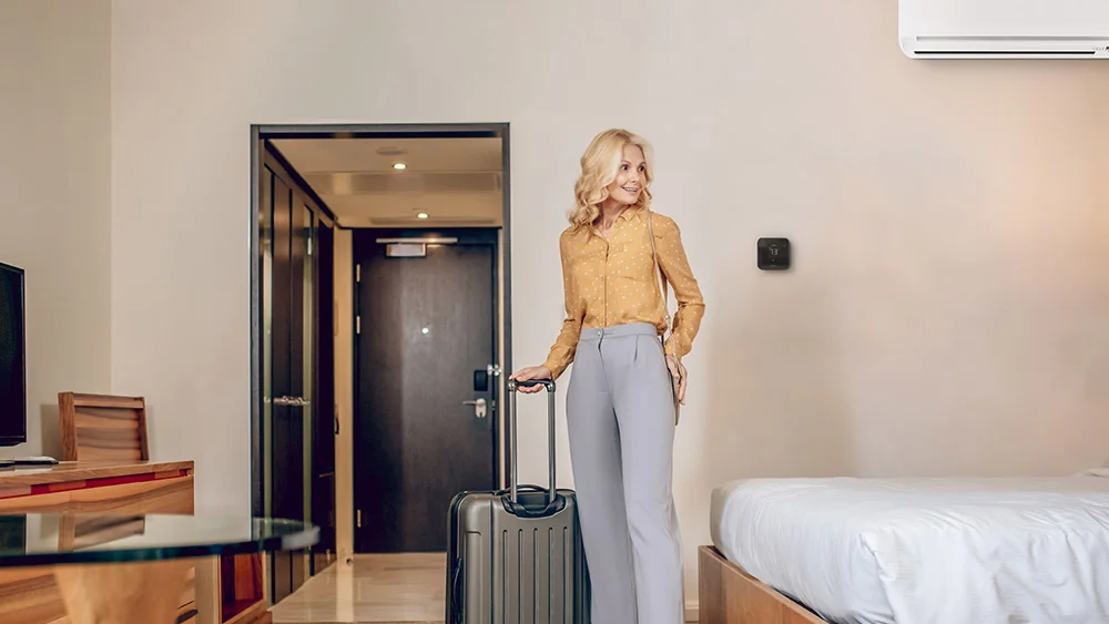 woman standing in vacation rental room with max device on the wall